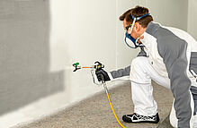 Handwerker sprüht Wand mit Emulsion an