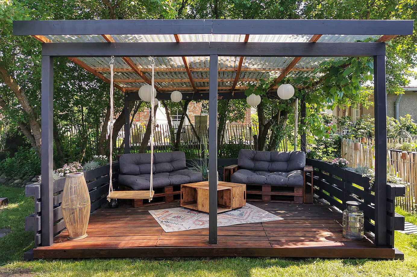 Fertig gebaute Terrasse aus Paletten mit Sofas und einer Schaukel