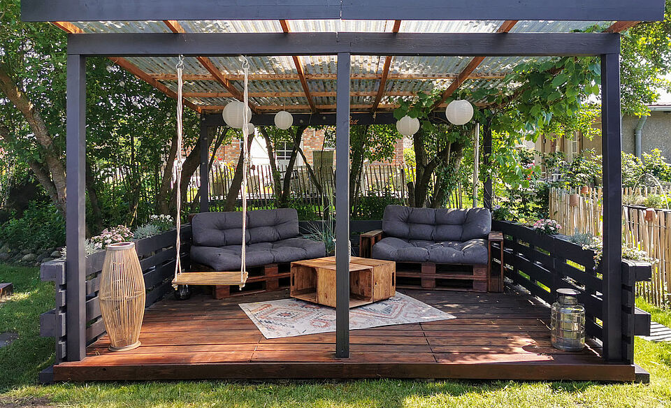Fertig gebaute Terrasse aus Paletten mit Sofas und einer Schaukel