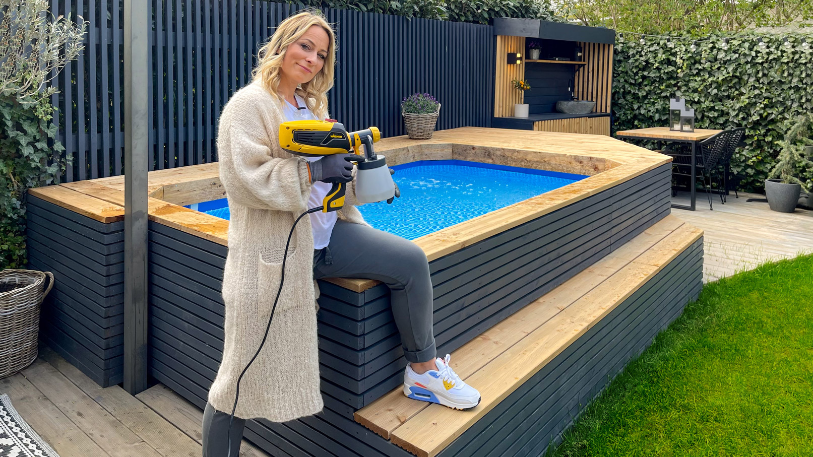 Aneta with paint sprayer in front of pool surround