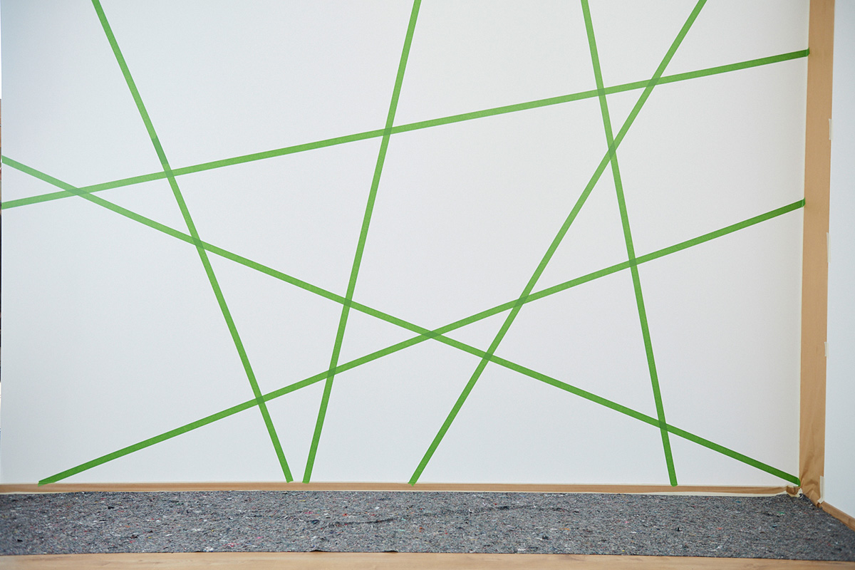 Coller des formes géométriques avec du ruban adhésif sur le mur