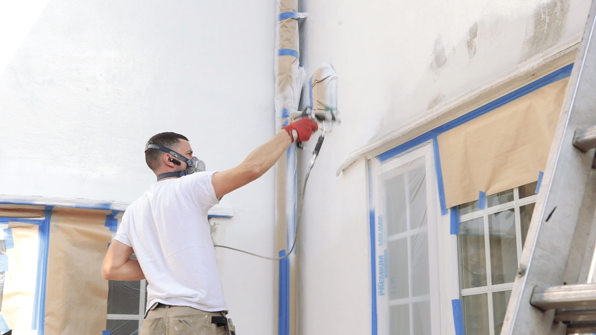 Uomo che dipinge muro grigio con pistola a spruzzo ristrutturazione di una  nuova casa aprire il contenitore con una vernice