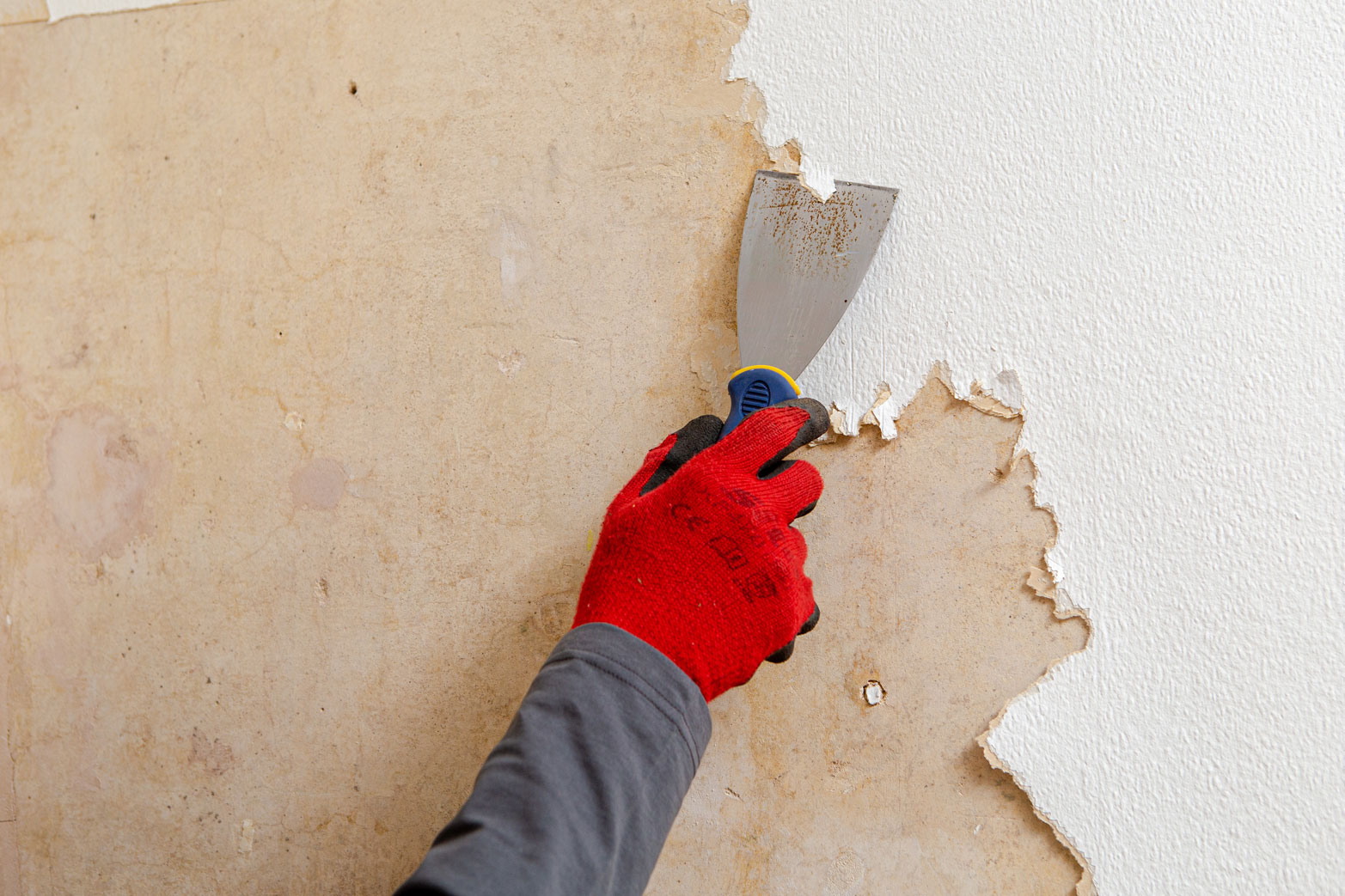Removing wallpaper with a scraper